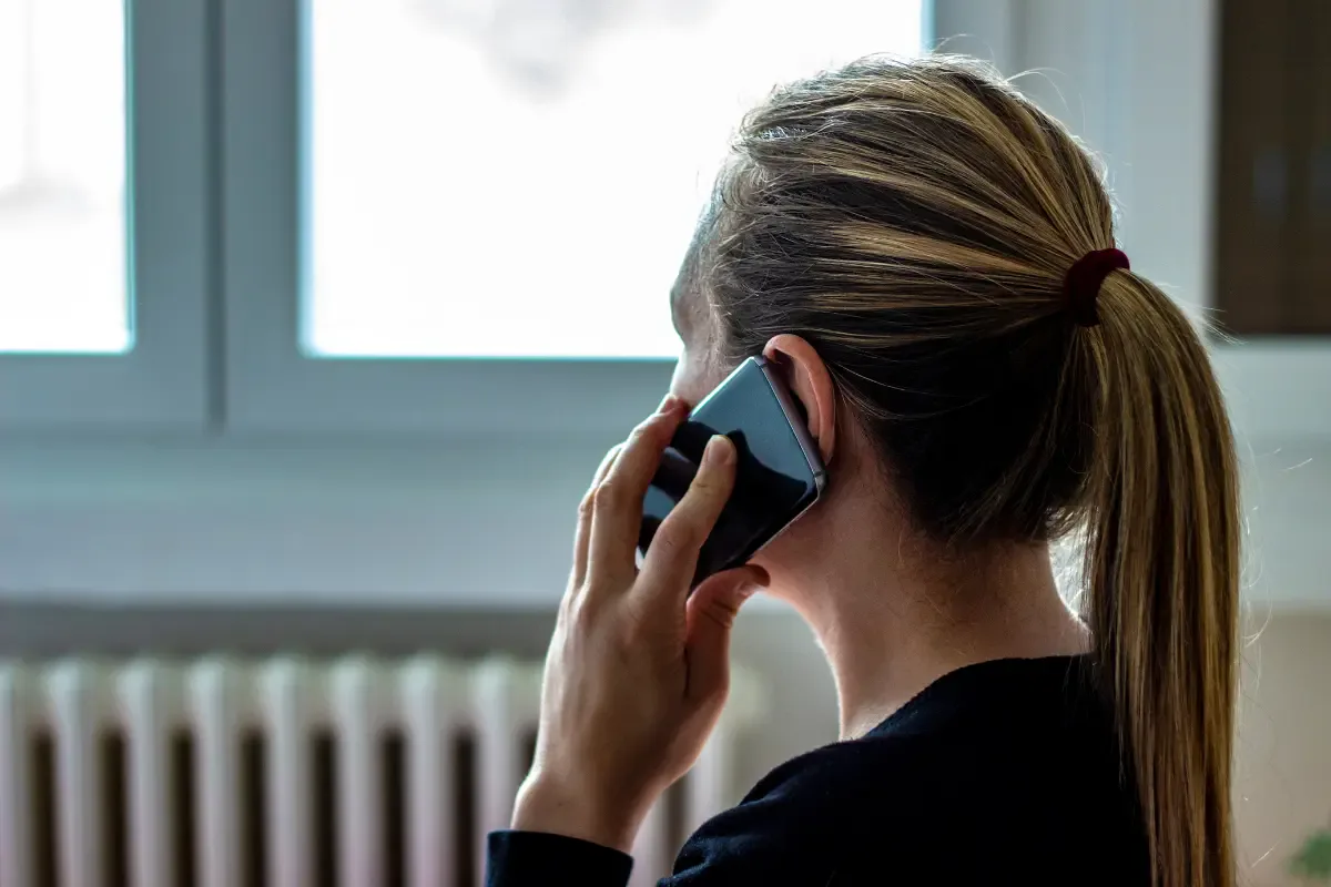 O persoană care privește suspicios ecranul unui smartphone ce afișează un apel de la un număr necunoscut.